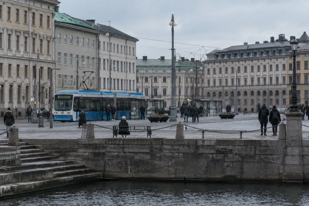 A blue Gothenburg tram at a street stop in the city centre on a grey day