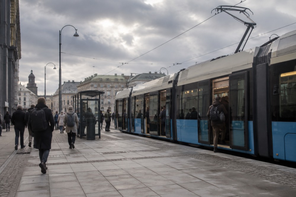A Gothenburg tram on a city street with passengers boarding at a stop