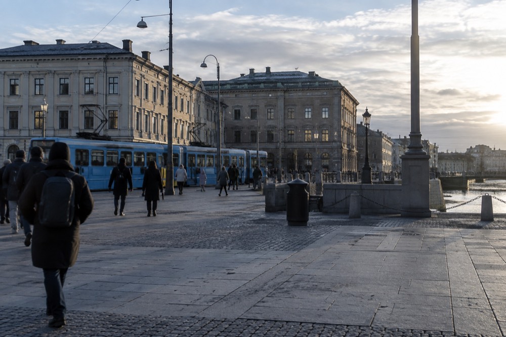 A blue Gothenburg tram passing brick buildings on a city street