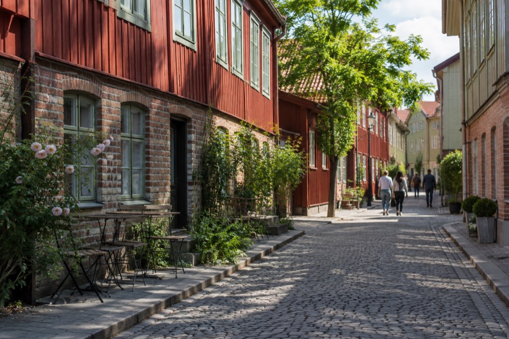 Red wooden buildings along a cobblestone street in the Haga quarter of Gothenburg on a bright day
