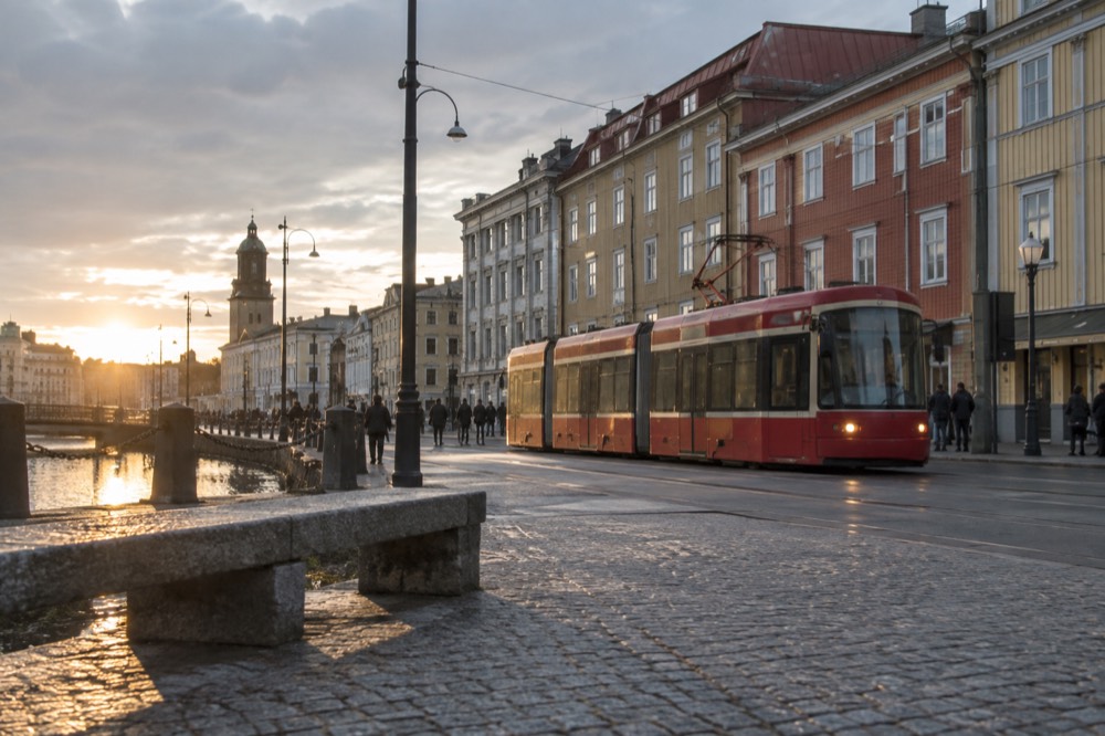 Red tram passing colourful wooden buildings on a Gothenburg street