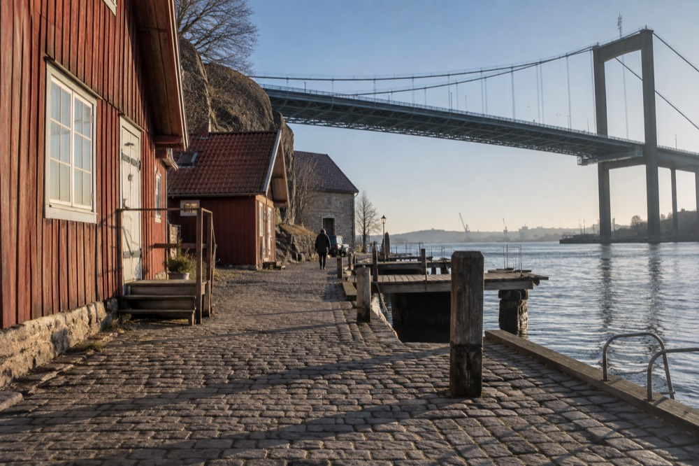 Old wooden harbour buildings at Klippan with the Älvsborg Bridge rising above them