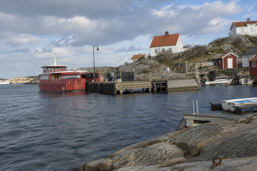 Red ferry boat at a wooden jetty on a rocky island in the Gothenburg archipelago