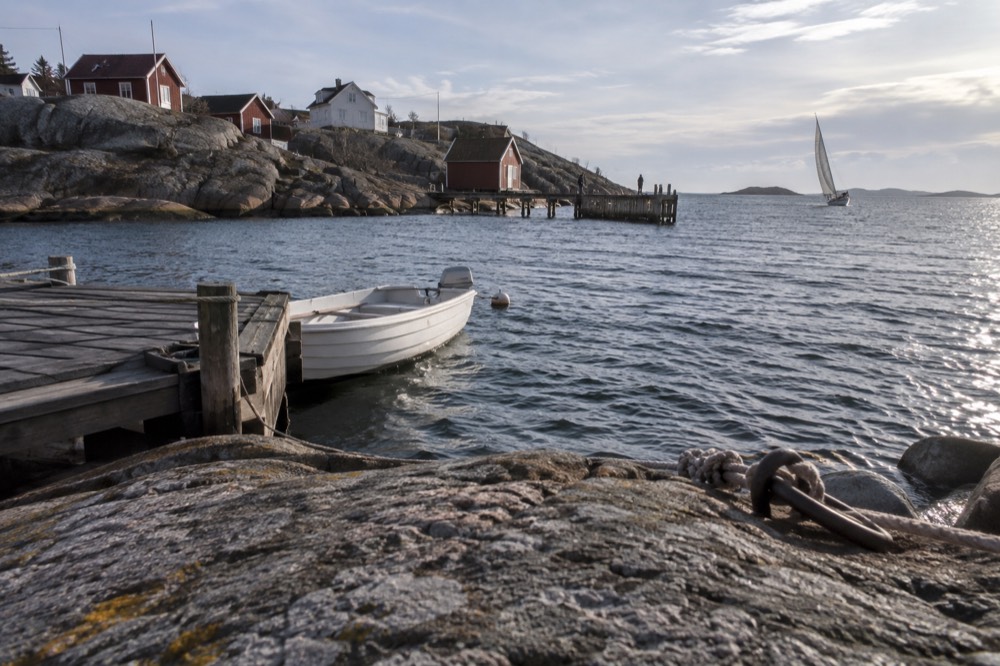 Small sailing boat heeling in open water between islands of the archipelago