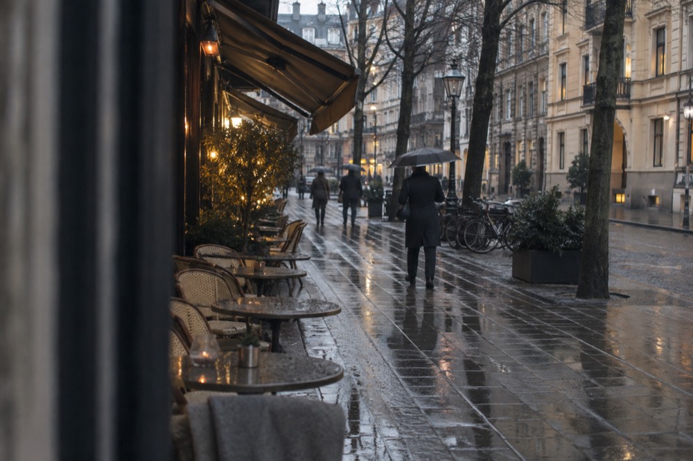 Rainy street in a stone district with wet pavement reflecting shop lights