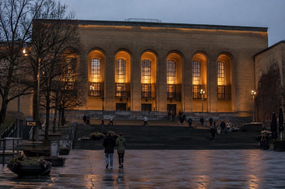 The art museum facade at dusk with warm light in the windows above the plaza