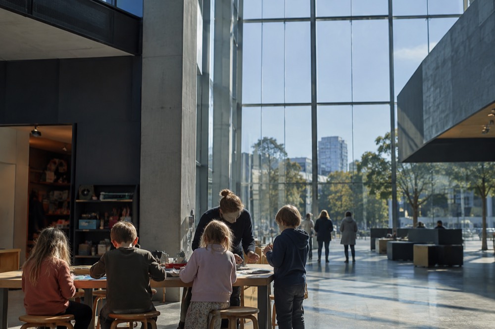 Children doing an activity at a museum workshop table with an adult guide