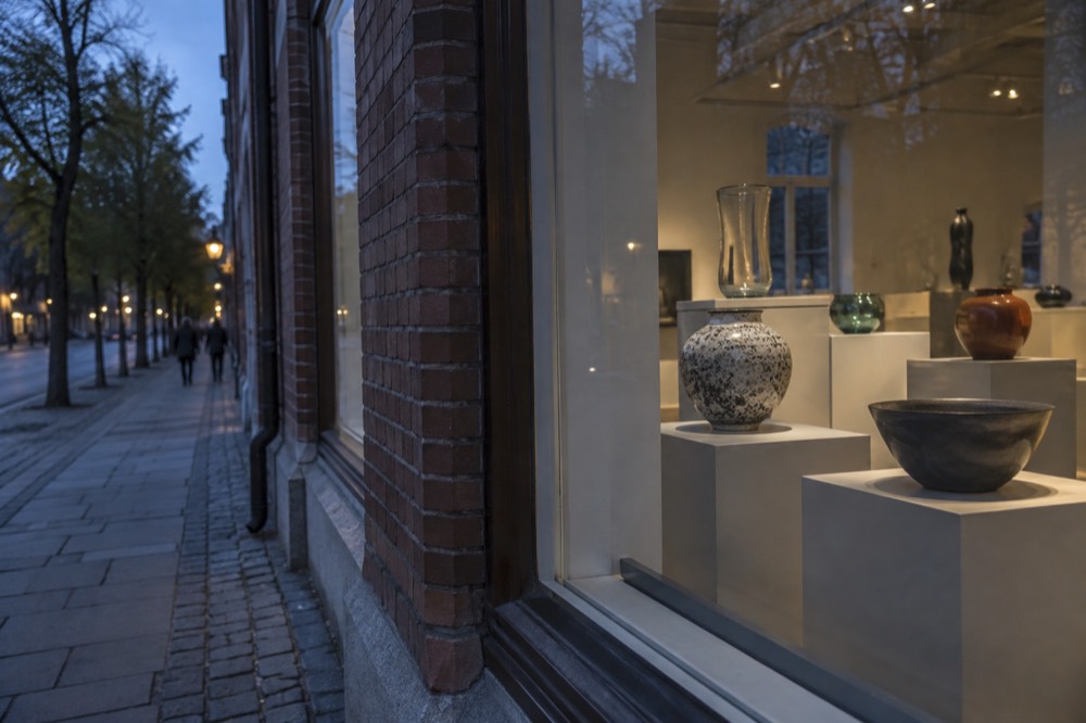 A display of ceramic vessels and glassware arranged on plinths in a museum case