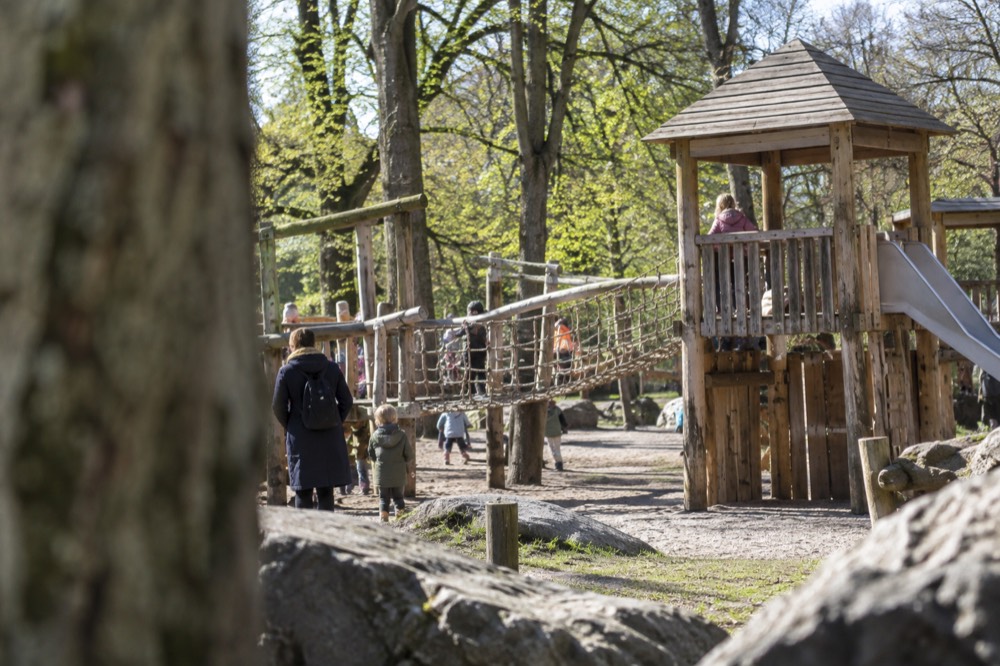 A large wooden playground with climbing frames and children playing