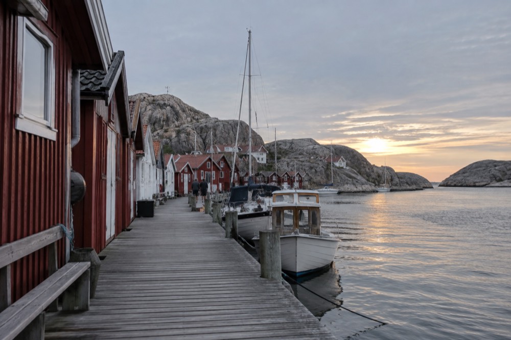 Red boathouses and smooth granite rocks along a Bohuslän harbour at dusk