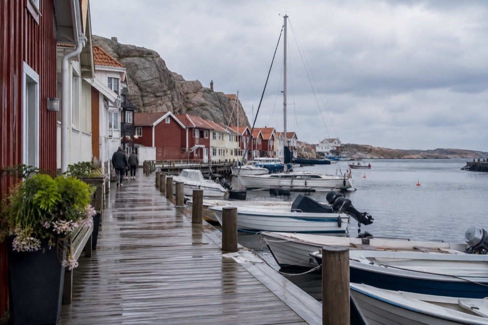 A long wooden pier with colourful shops along a small harbour