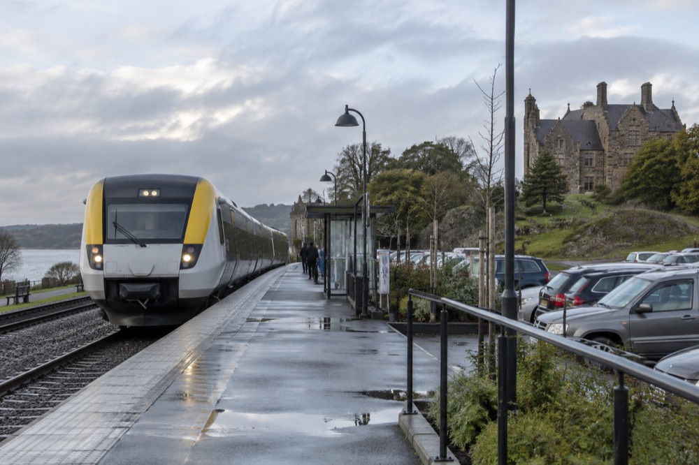 A regional train at a small station platform beside a park-and-ride area