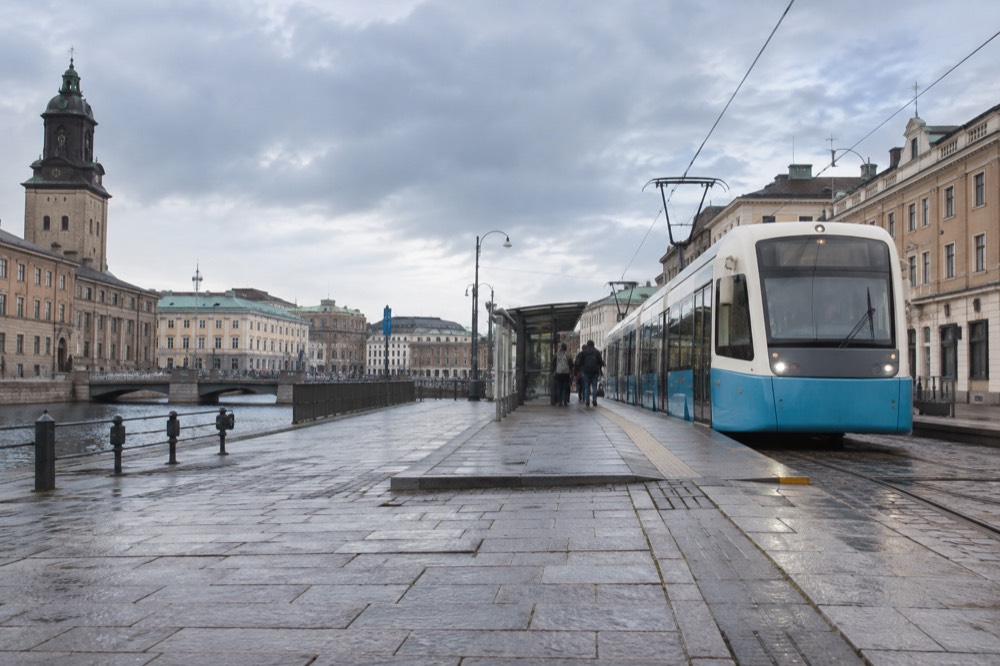 A low-floor Gothenburg tram at a platform in the city centre on a grey day