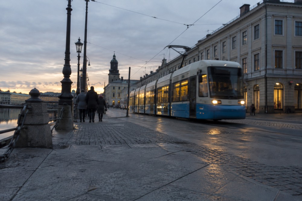 A tram moving through a stone street in Gothenburg at dusk