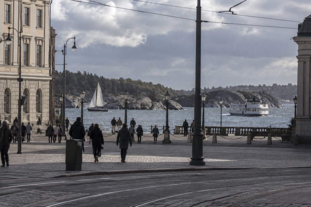 A small sailing boat and a ferry passing between granite islands in the archipelago