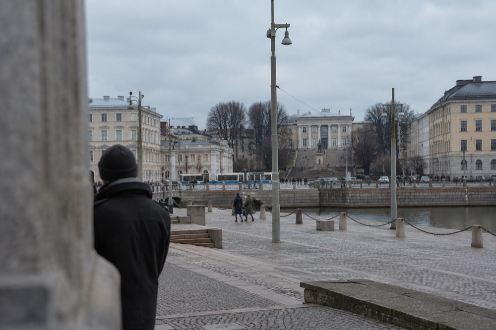 A tree-lined city boulevard with a statue and museum steps at its far end