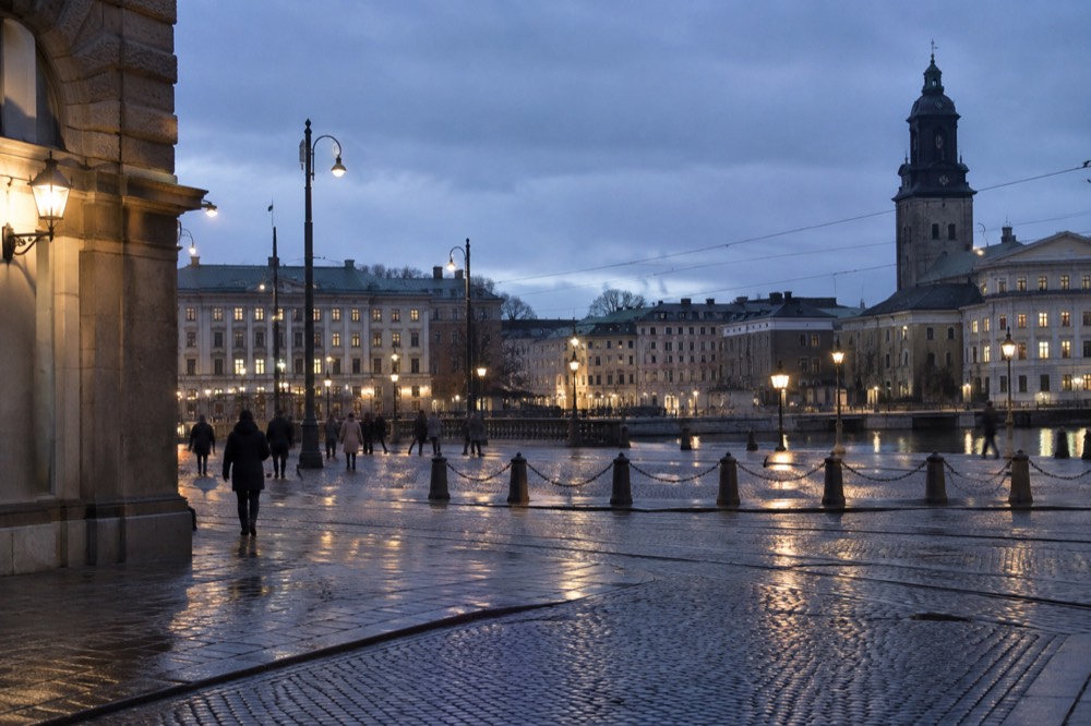 Rain-slicked cobblestone street in Gothenburg's old town under street lights