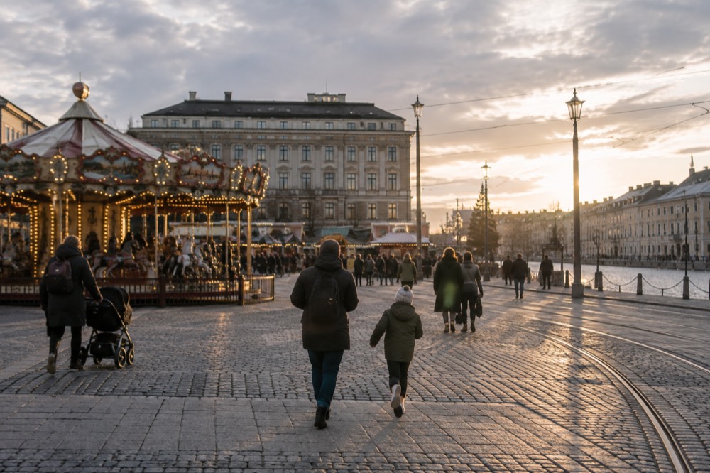 A vintage carousel and families walking through a Scandinavian amusement park