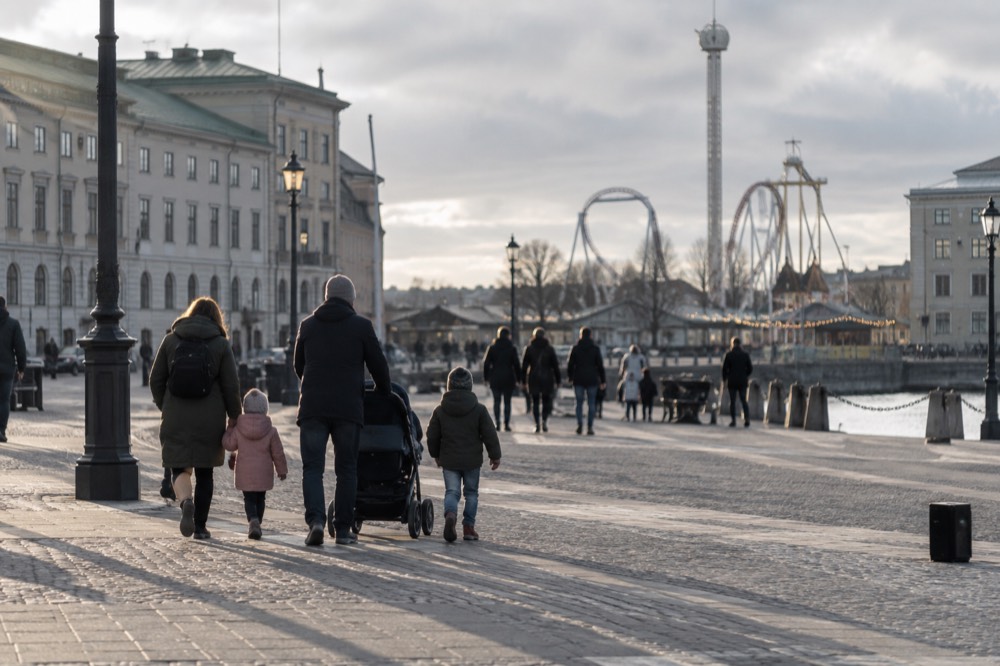 Families walking through a Scandinavian amusement park with a tall ride in the background