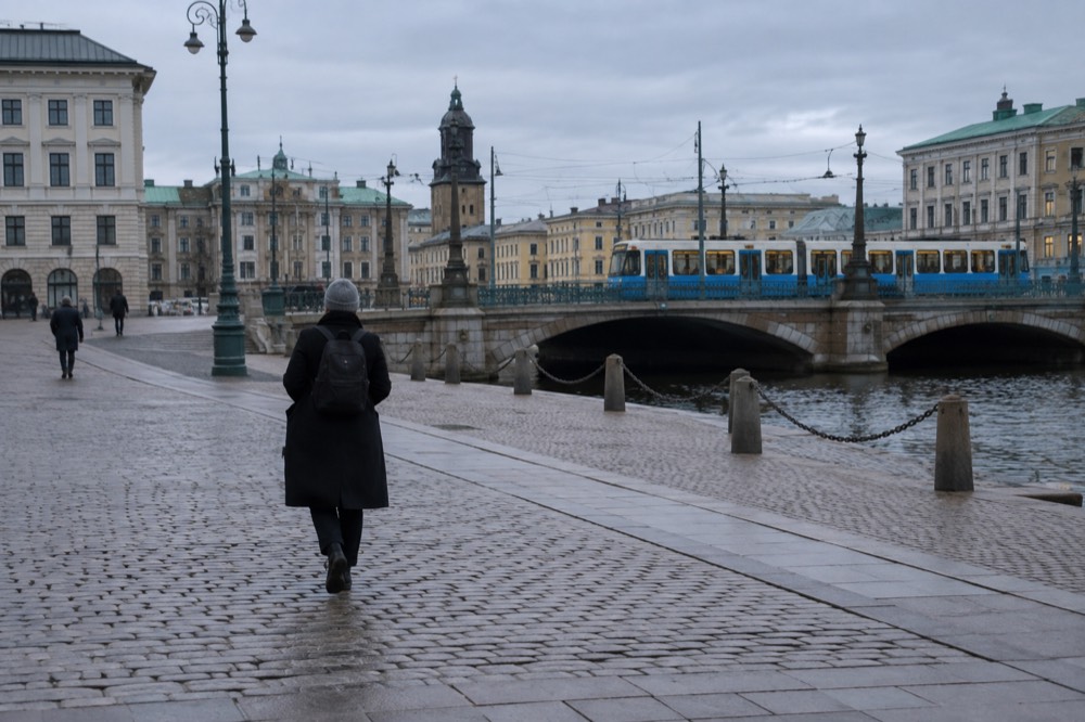 A blue Gothenburg tram crossing a stone bridge over a canal