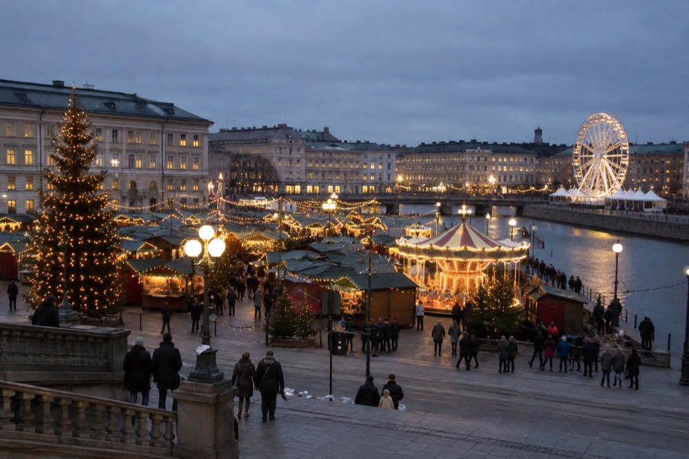 Festive lights and a ferris wheel glowing over a Scandinavian Christmas market at dusk