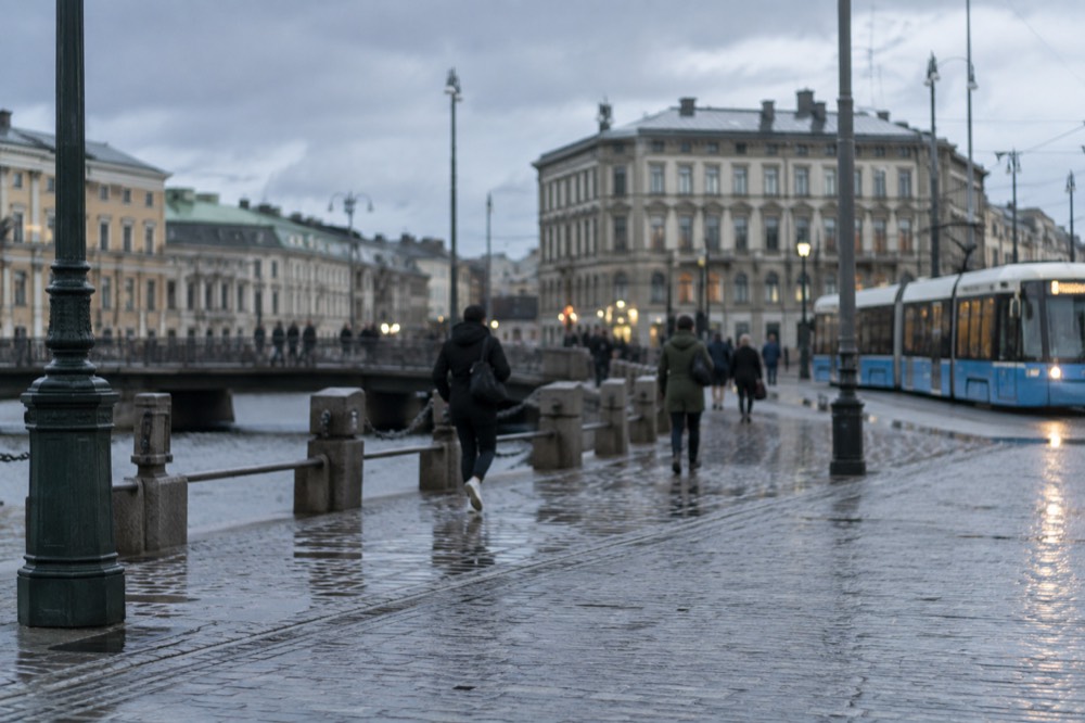 A tram moving along a Gothenburg street with granite buildings under grey sky