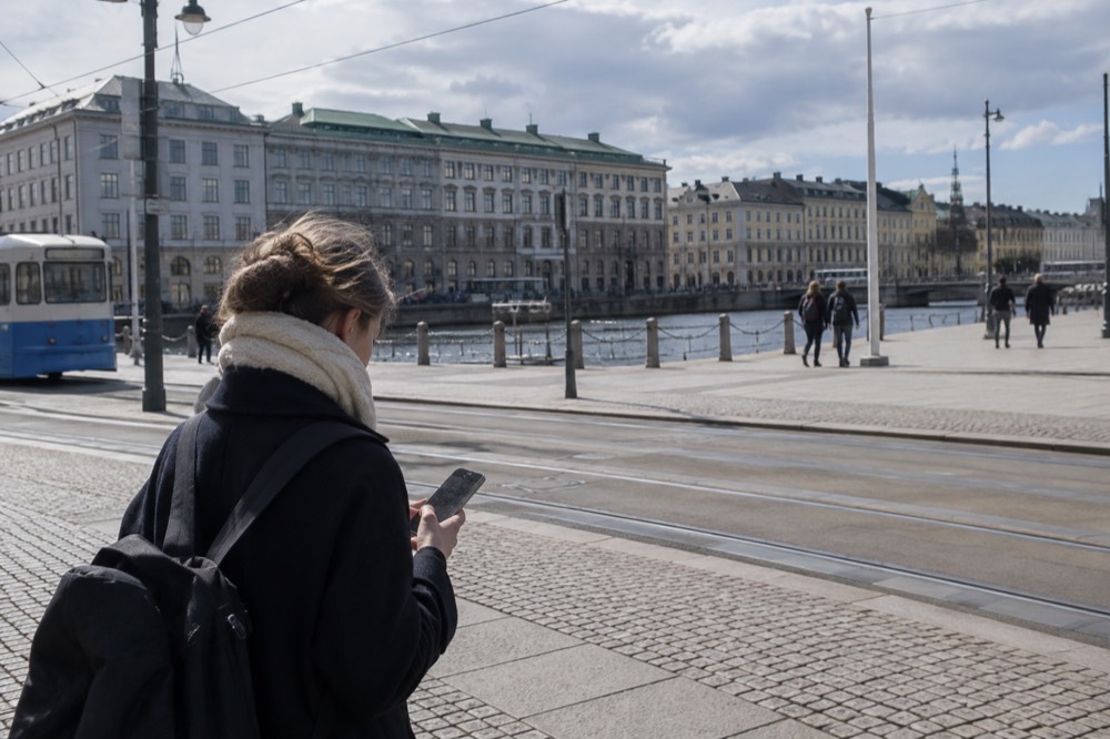 A traveller checking a train ticket on a phone at a station platform