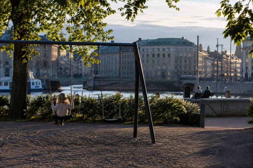A child on a swing in a Gothenburg park under long evening summer light