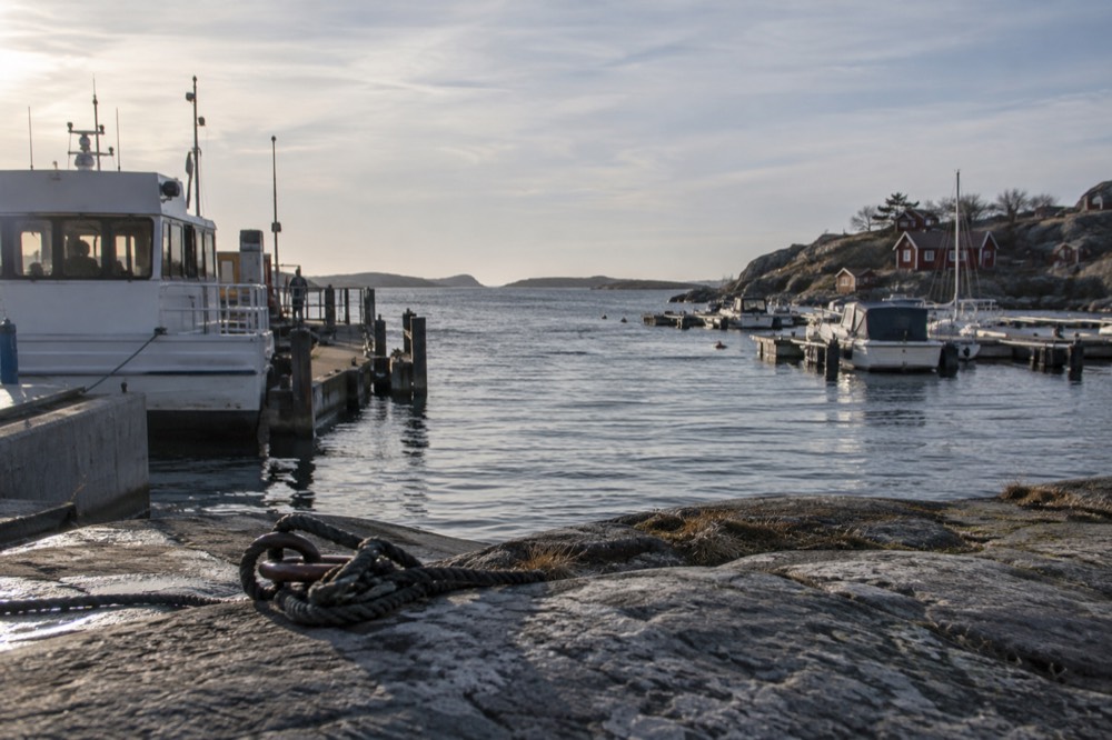 Red wooden boathouses along a rocky shoreline on a car-free island near Gothenburg
