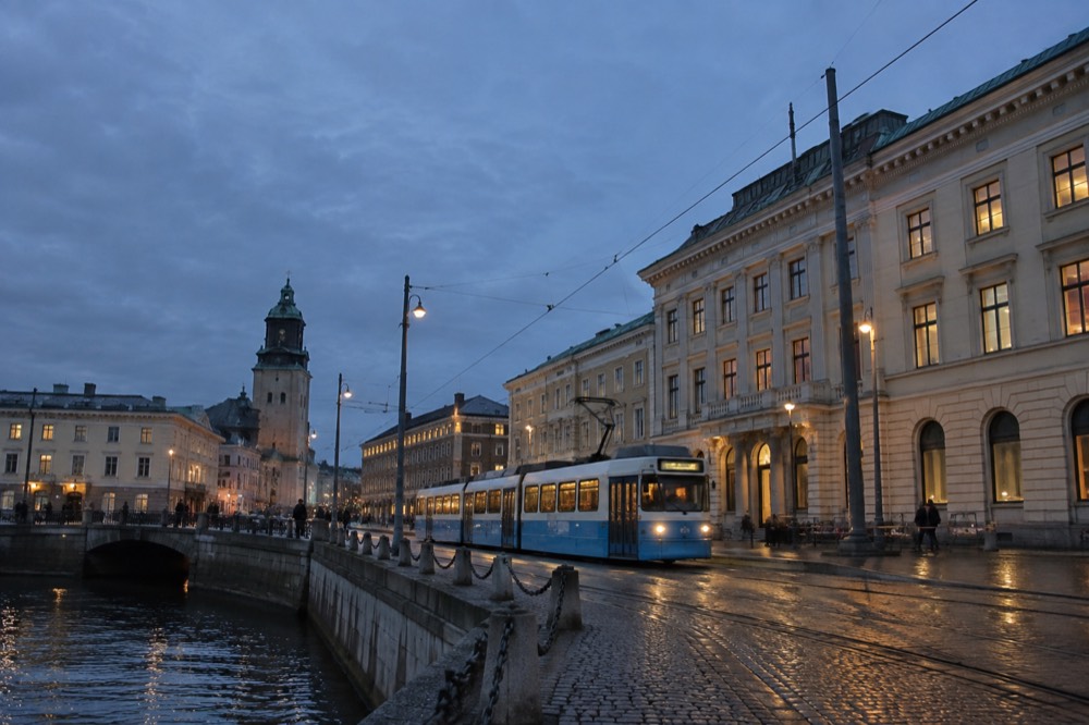 A Gothenburg tram passing stone buildings on a quiet evening street
