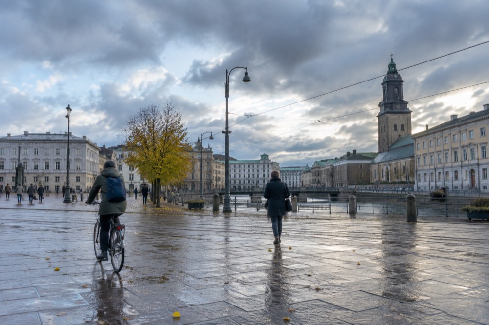 A cyclist and pedestrian on a rain-wet Gothenburg street in autumn