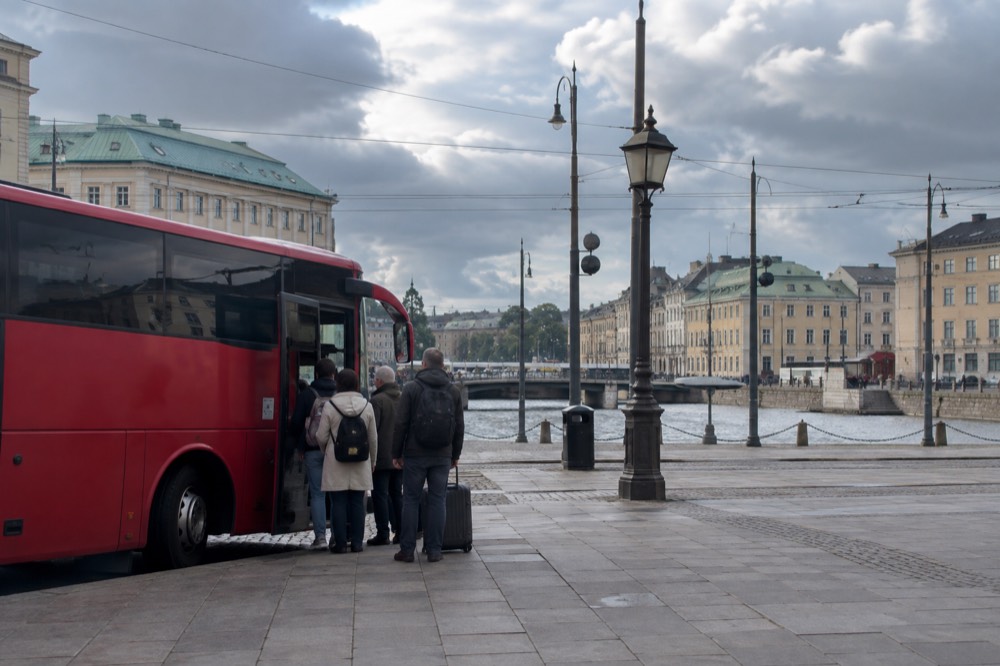 Red airport coach waiting at a terminal stand with passengers boarding