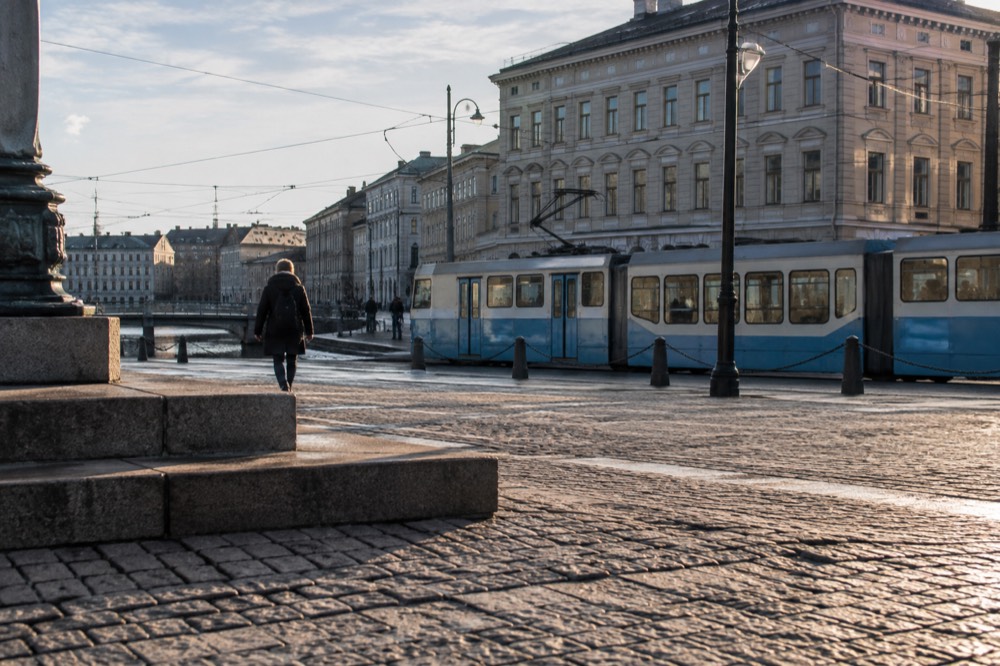 Tram moving along a city street with stone buildings behind it