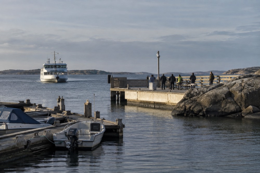 A ferry approaching a small island jetty where cyclists and walkers wait