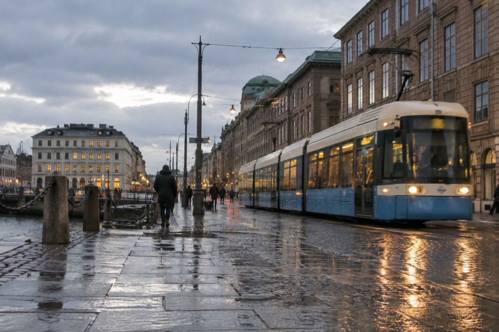 A Gothenburg tram passing brick buildings on a rainy evening street