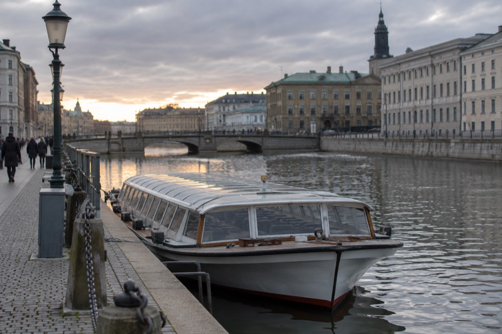 A canal tour boat moored at a quay in Gothenburg at golden hour