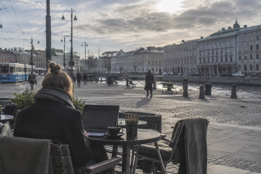 A visitor using a laptop on free WiFi at a cafe table in Gothenburg