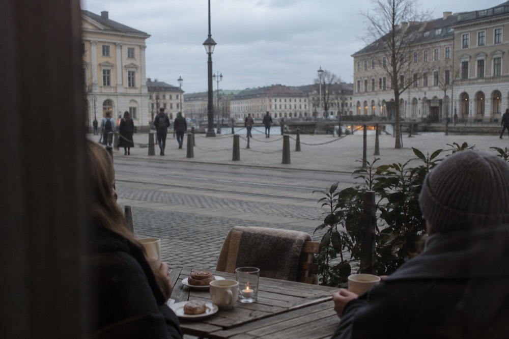 People sharing coffee and pastries at a wooden table in a Gothenburg cafe