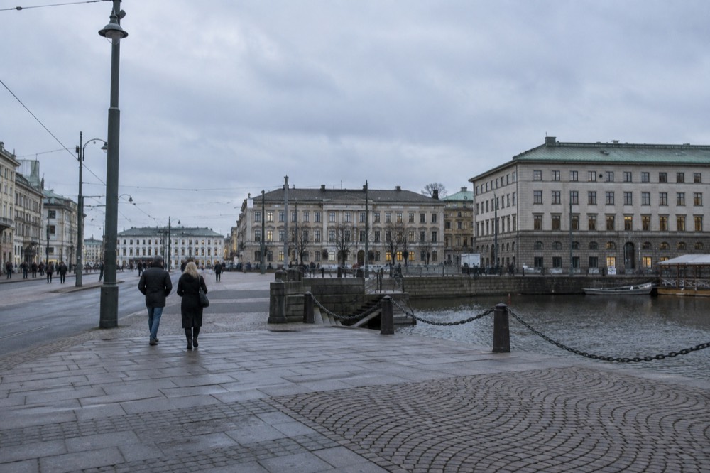 A couple studying a map on a Gothenburg street with cafés and stone buildings