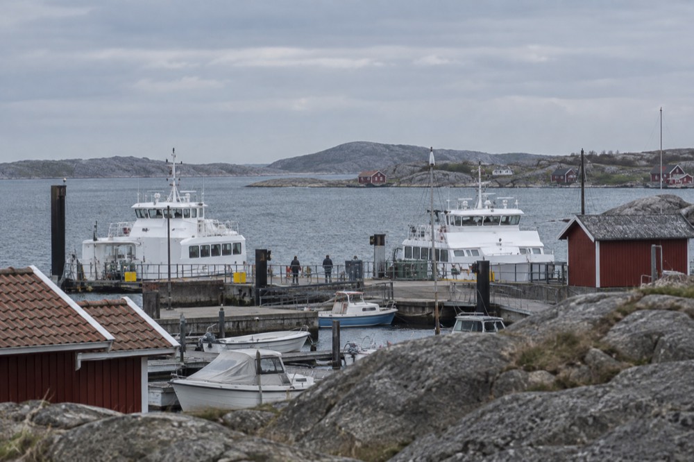 Red wooden boathouses along a rocky shoreline on a small Swedish island
