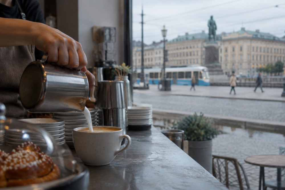 Oat milk being poured into a coffee cup on a cafe counter in Gothenburg