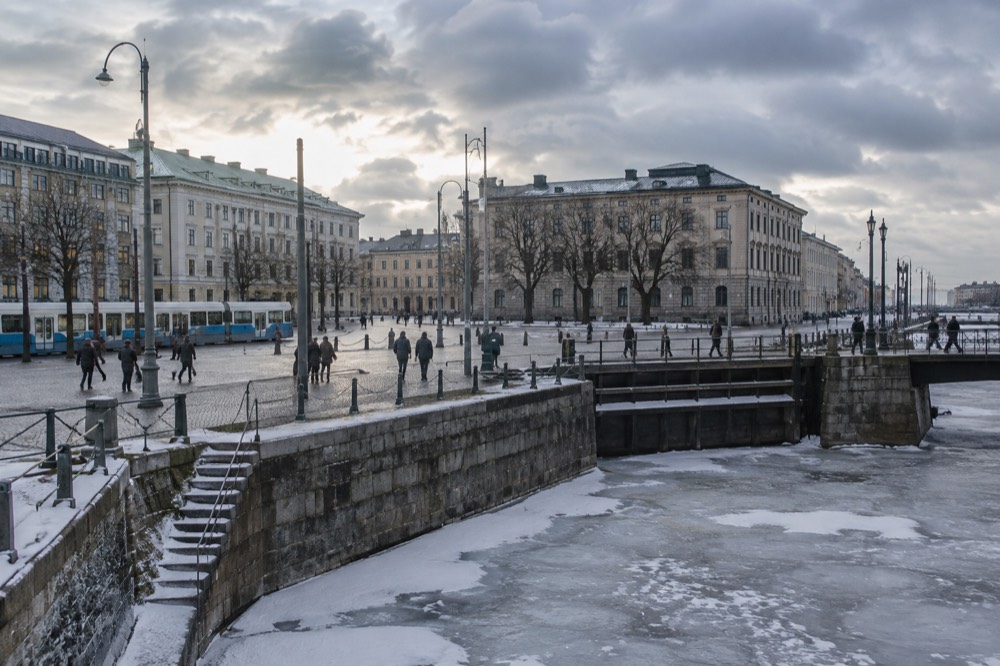 Canal lock gates and a stone embankment beside a frozen river in winter