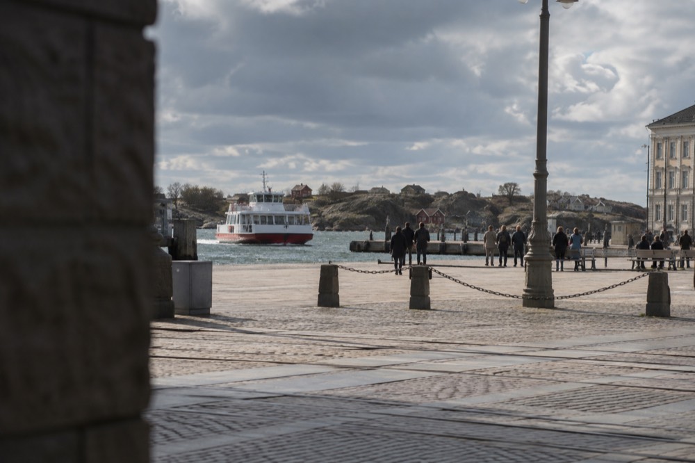 Red and white ferry approaching a rocky car-free island with small wooden cottages